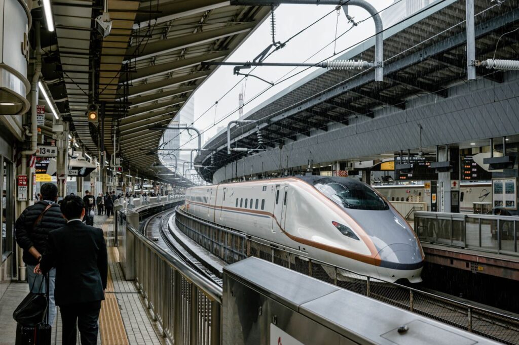 A high-speed Shinkansen train arrives at a busy Tokyo station platform, showcasing modern transport.